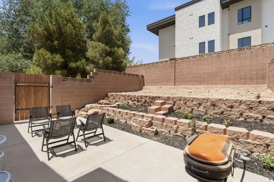 Tiered backyard featuring a concrete patio, retaining walls, and a wood gate