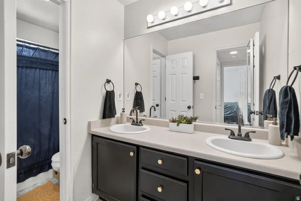 Double vanity with integrated sinks, dark cabinetry, and light-toned countertops