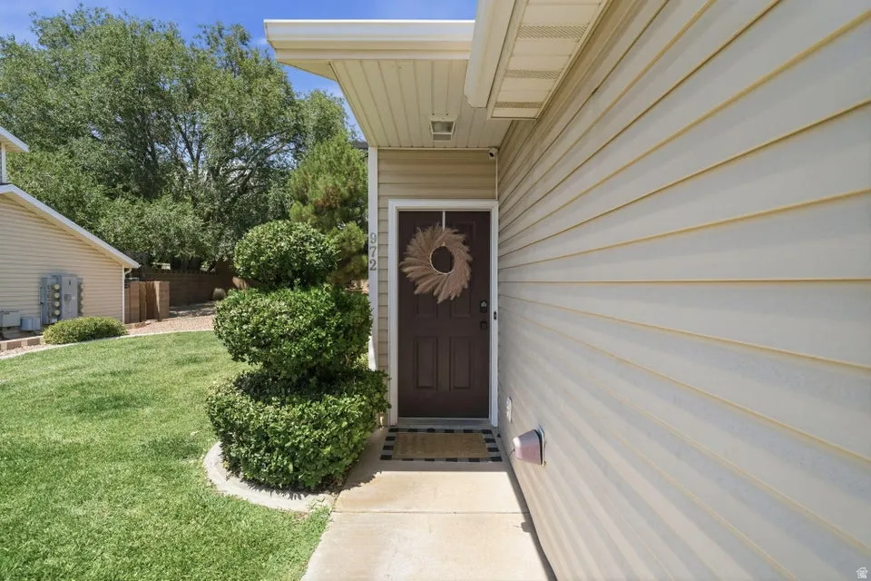Entryway featuring a dark brown door with sidelights, neutral-toned siding, and a concrete walkway