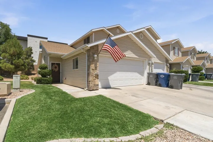 Exterior featuring light-colored siding, a two-car garage, and stone accents