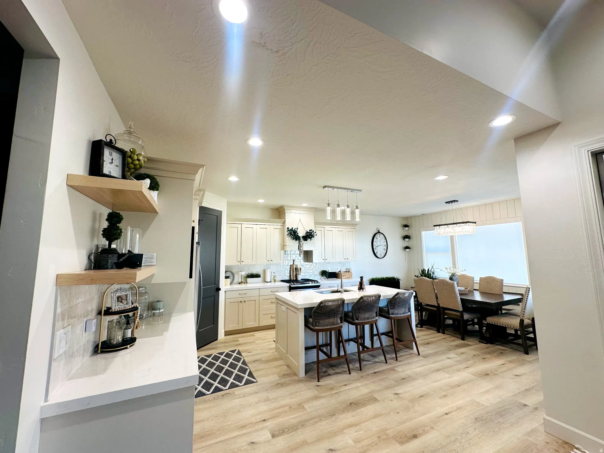 Open-concept living space featuring wood-finish flooring, recessed lighting, and a kitchen island with seating