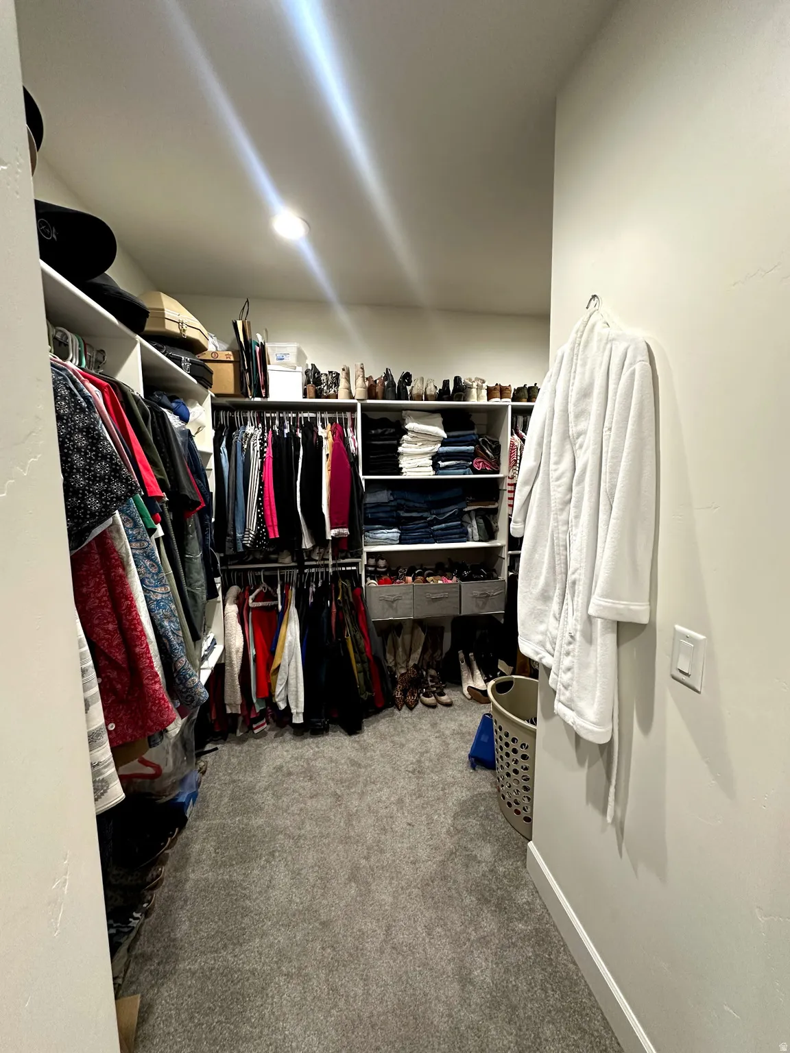 Custom closet system featuring multiple hanging rods, integrated shelving, and recessed lighting