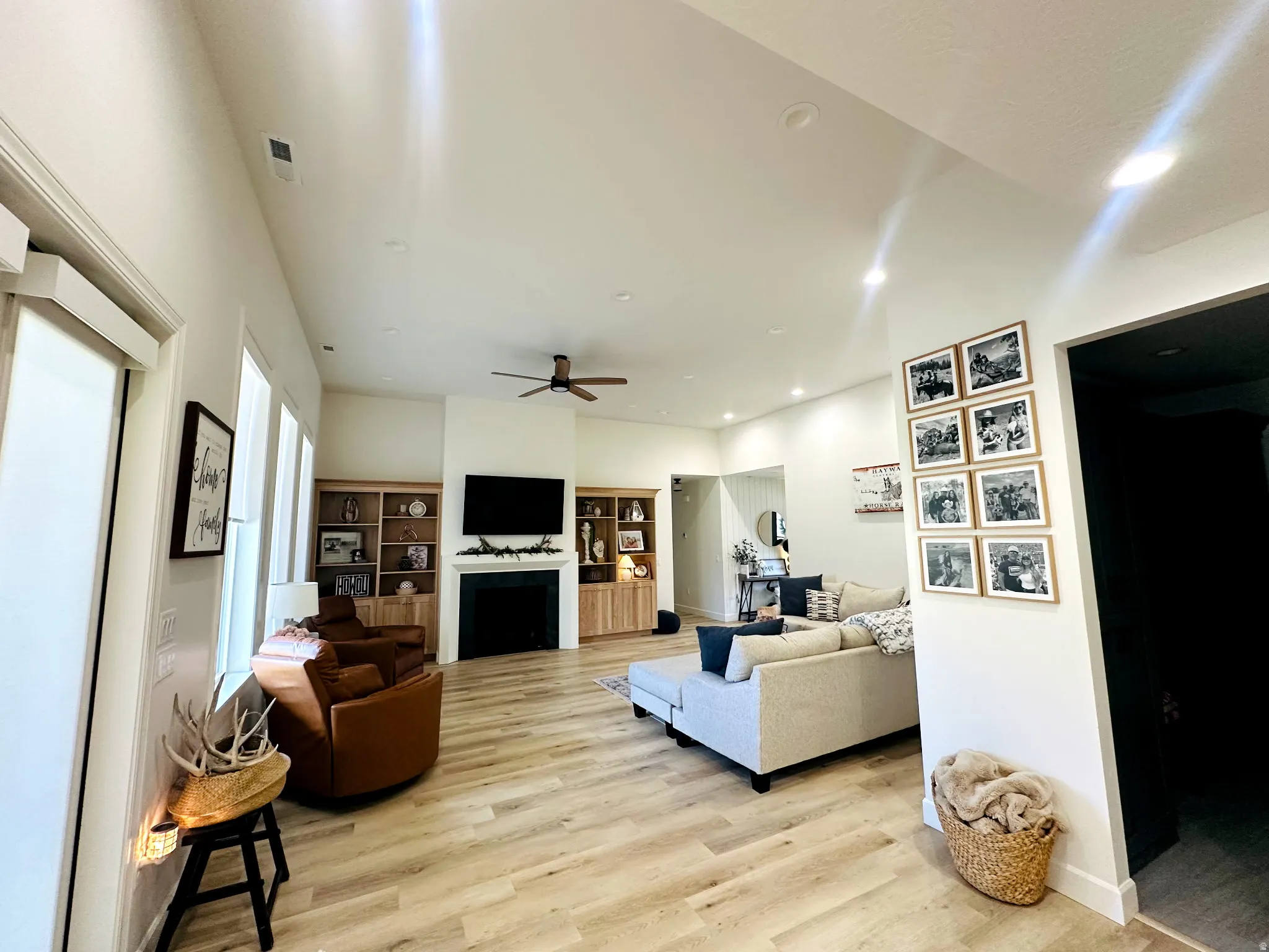 Spacious living area featuring light wood-finish flooring, recessed lighting, and a ceiling fan