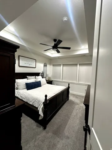 Tray ceiling featuring recessed lighting and a ceiling fan, plush gray carpet flooring, and a wall of windows