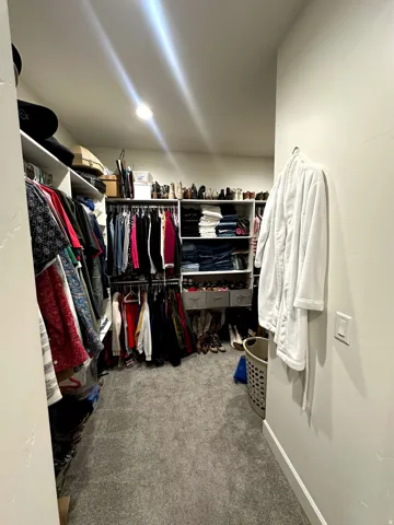 Custom closet system featuring multiple hanging rods, integrated shelving, and recessed lighting
