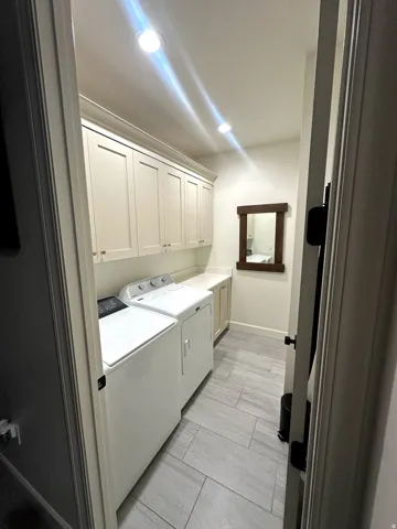 Dedicated laundry space featuring extensive upper cabinetry, a built-in countertop, tile flooring, and integrated ceiling lighting
