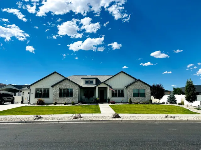Modern home exterior featuring stone and board-and-batten siding, a prominent gable roofline, and a manicured lawn