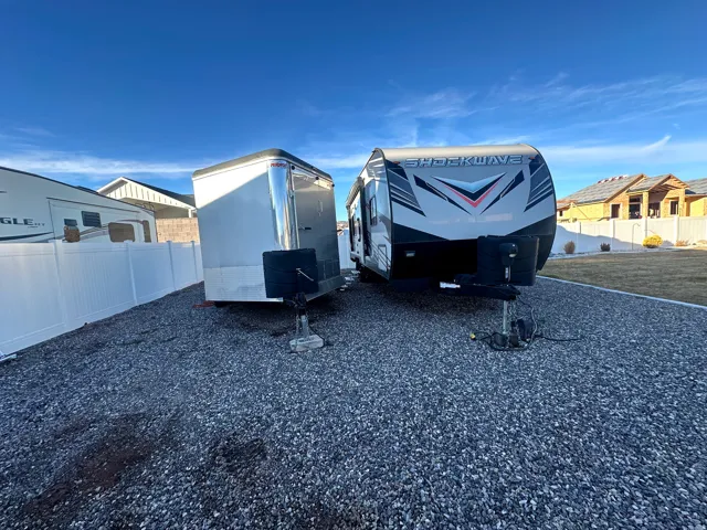 Gravel parking area featuring a white vinyl fence and a grassy perimeter