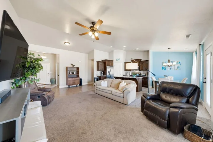 Open-concept living area featuring vaulted ceilings, recessed lighting, and a ceiling fan
