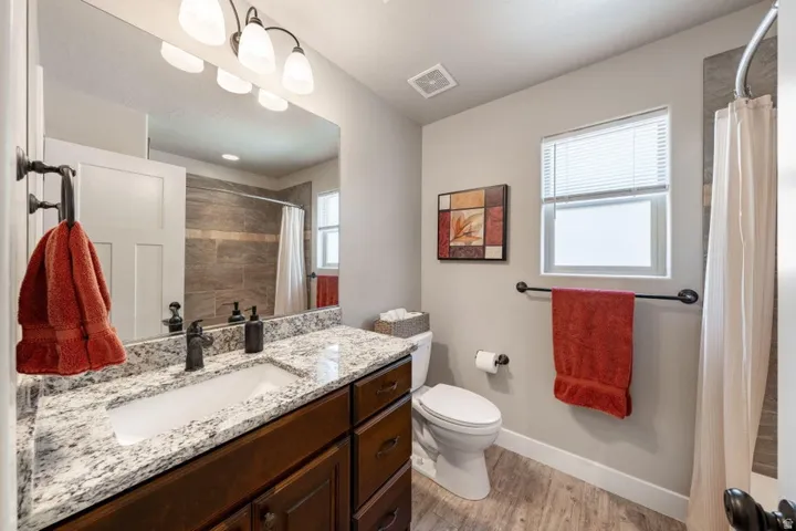 Bathroom featuring a dark wood-finish vanity with a granite countertop, undermount sink, and dark bronze-finish fixtures
