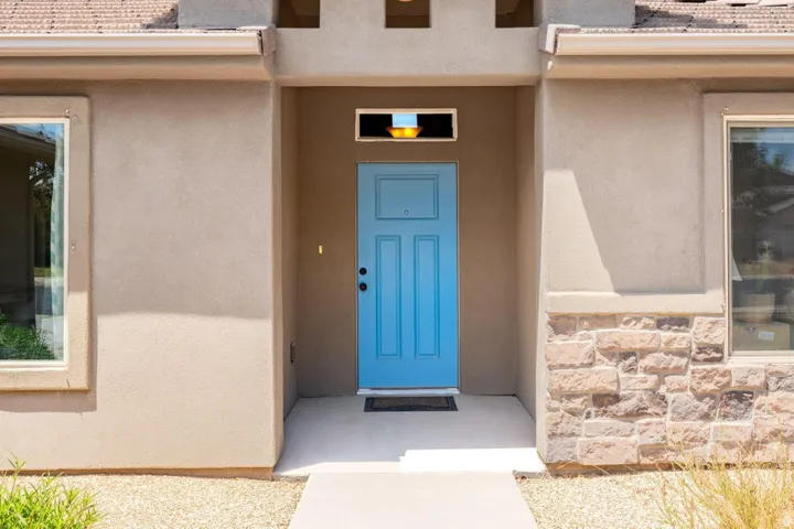 Inviting entry featuring a bright blue paneled door, transom window, and exterior lighting