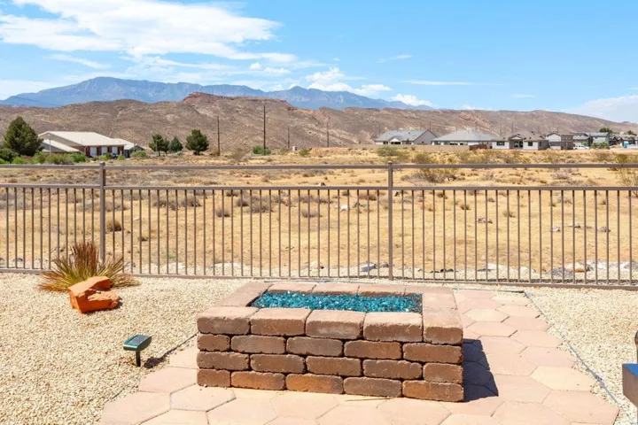 Outdoor patio featuring a brick fire pit with blue glass elements, set on hexagonal pavers