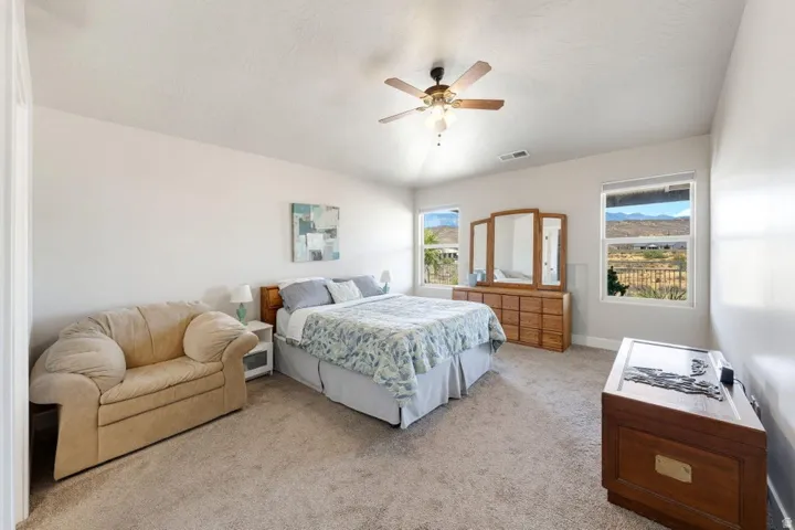 Spacious room featuring light-colored walls, carpeted flooring, and multiple windows