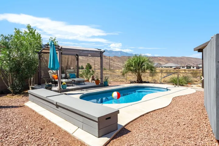Freeform swimming pool with integrated steps, surrounded by concrete decking and decorative rock landscaping