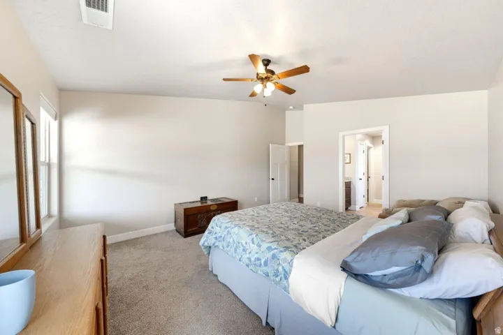 Carpeted room featuring a ceiling fan with integrated lighting, a window with natural light, and a white interior door