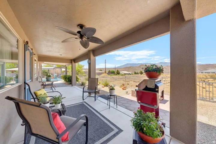 Spacious covered patio featuring a ceiling fan, concrete flooring, and an open-air design