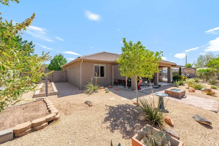 Xeriscaped backyard featuring a covered patio, flagstone pathway, and built-in fire pit