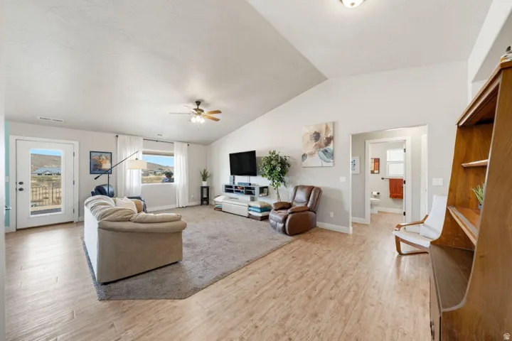 Spacious living area featuring a vaulted ceiling and wood-finish flooring