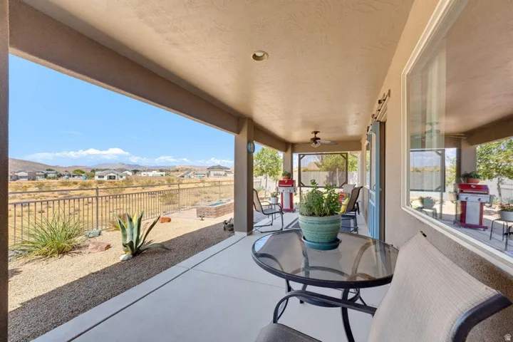 Expansive covered patio featuring concrete flooring, a ceiling fan, recessed lighting, and a desert-landscaped yard with a perimeter fence