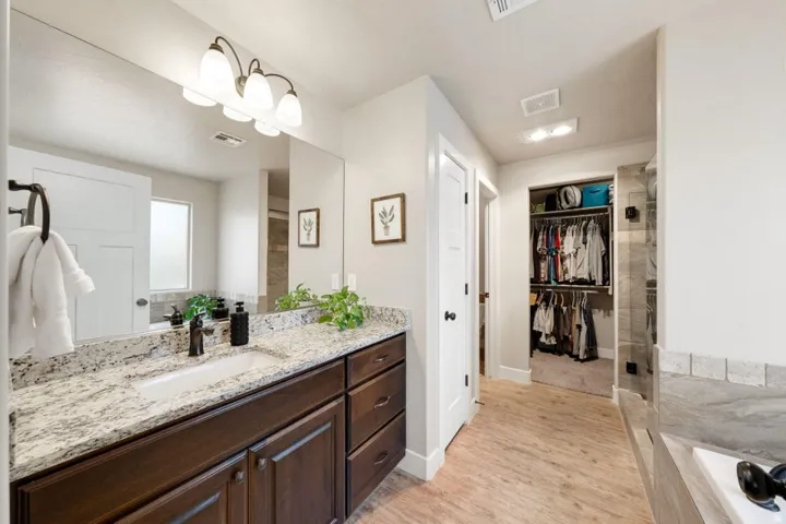 Spacious bathroom vanity featuring an undermount sink, a granite countertop, and dark wood cabinetry