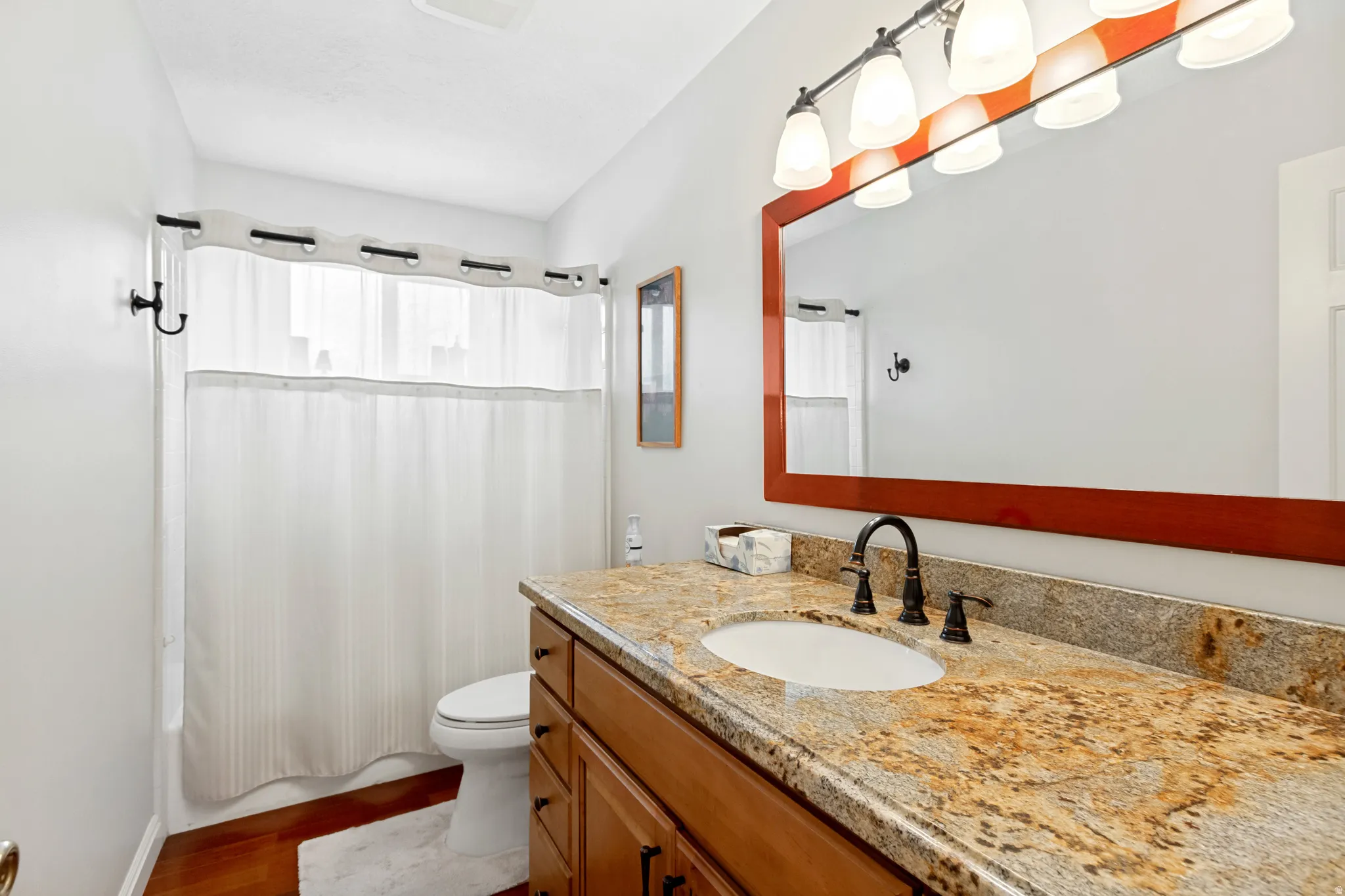 Bathroom featuring a broad vanity with a stone-finish countertop, a single undermount sink, and a dark bronze faucet