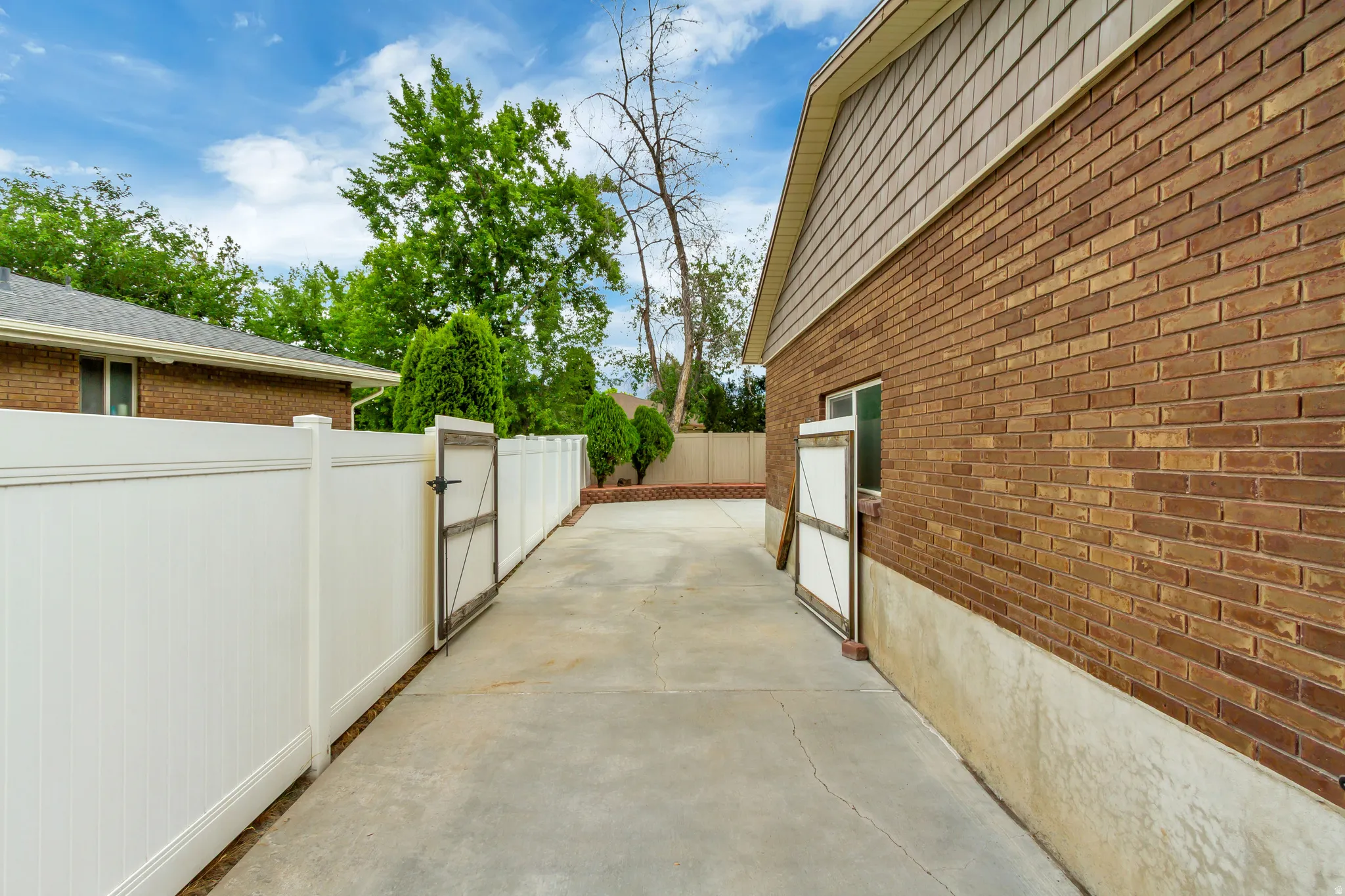 Concrete driveway with white vinyl fencing and two gates