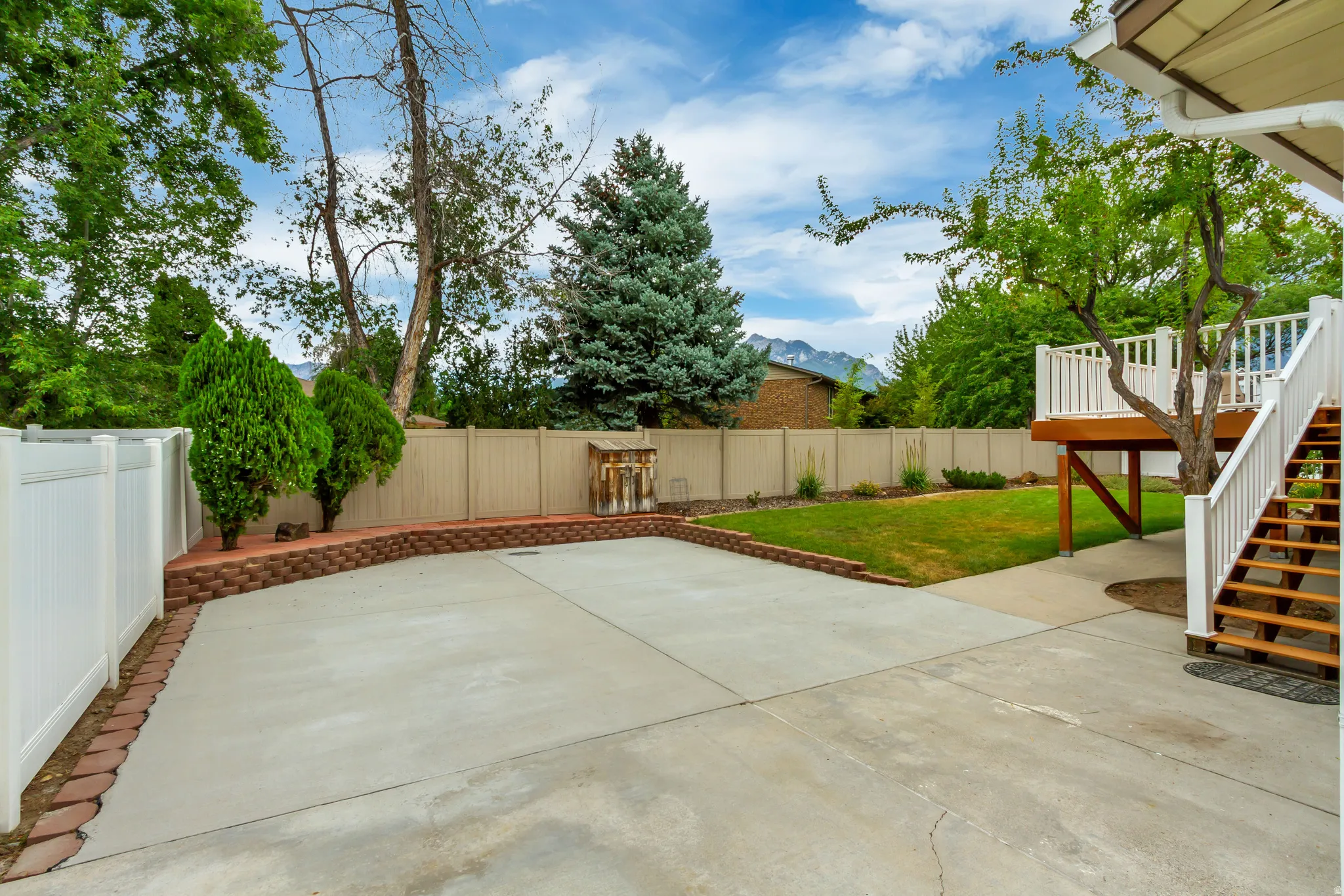 Spacious concrete patio featuring a brick-lined retaining wall