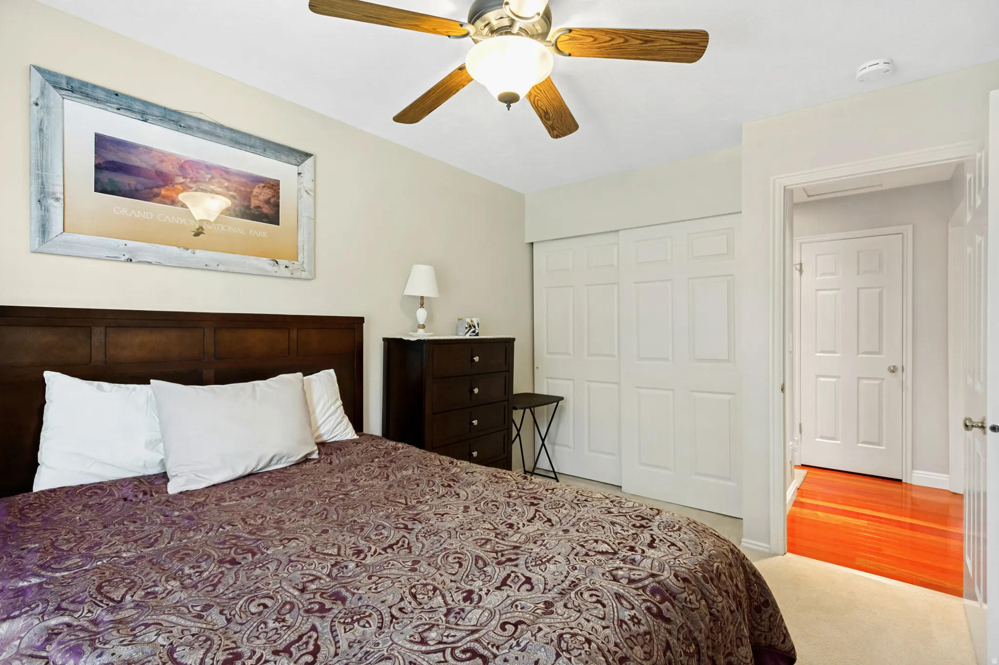 Bedroom featuring a ceiling fan with light, plush carpet flooring, and a paneled sliding closet door