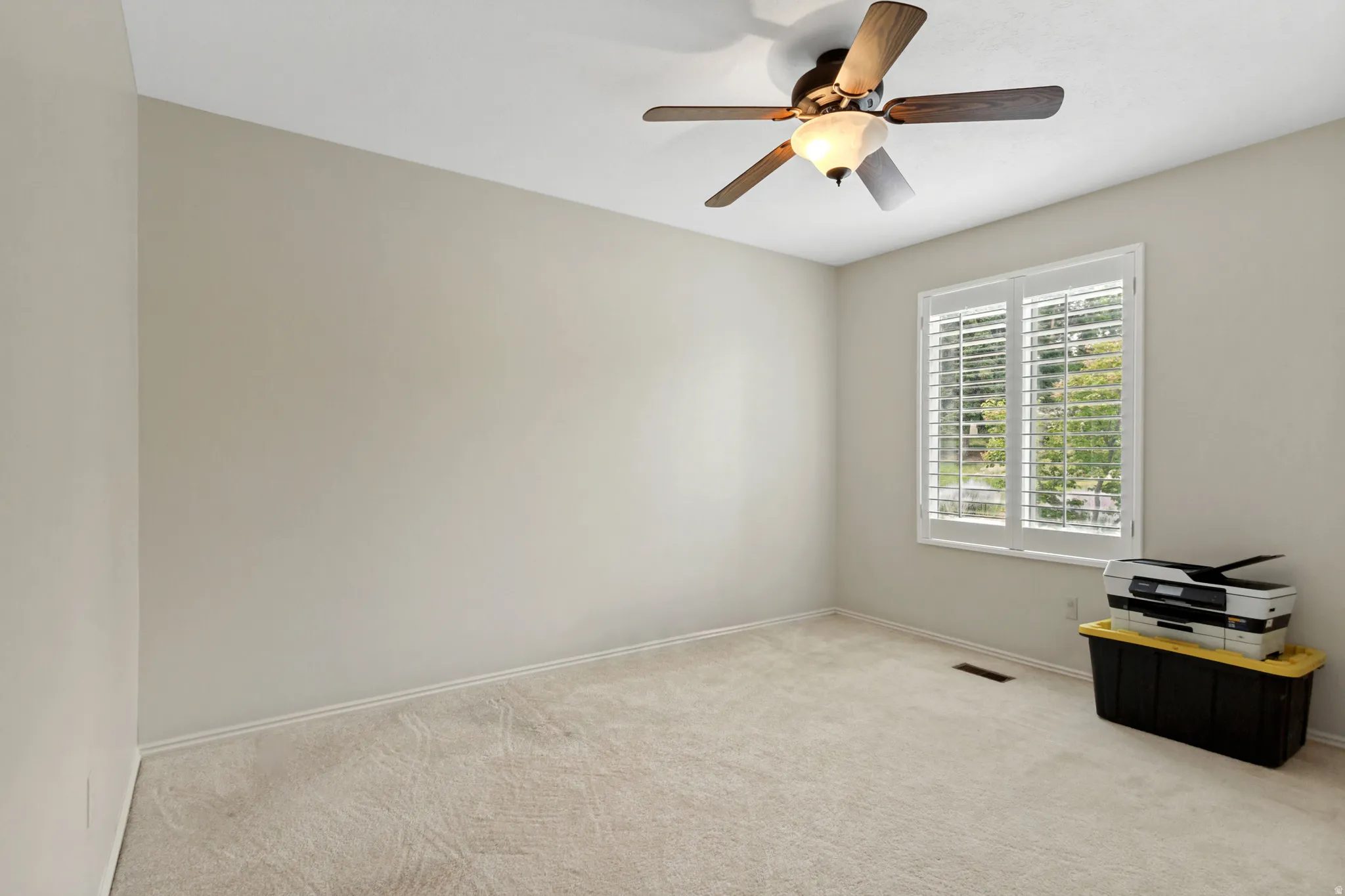 Room featuring light neutral wall paint, white trim, carpet flooring, and a ceiling fan with integrated lighting