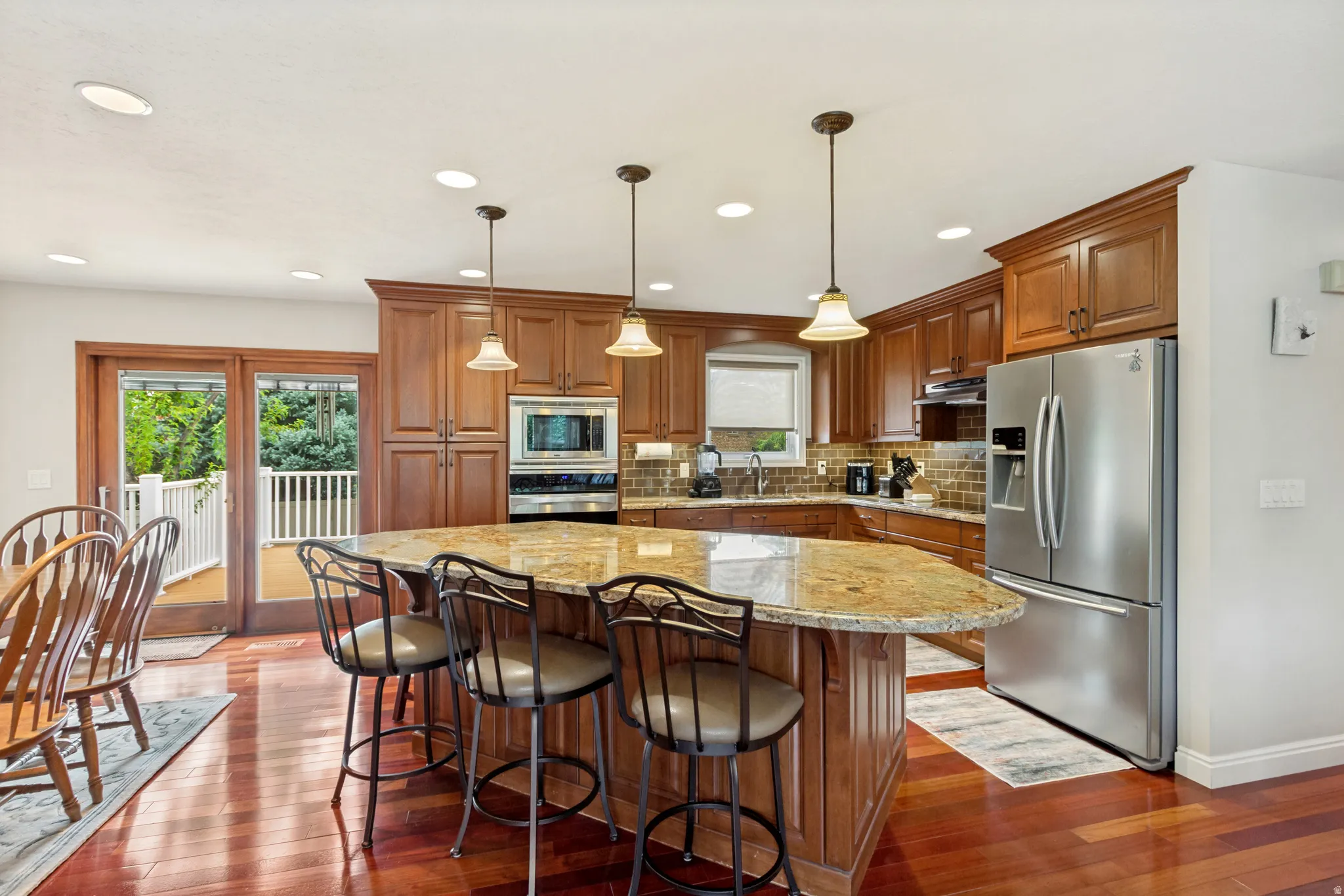 Kitchen featuring rich wood cabinetry, stainless steel appliances, a large center island with seating, a tile backsplash, and recessed lighting