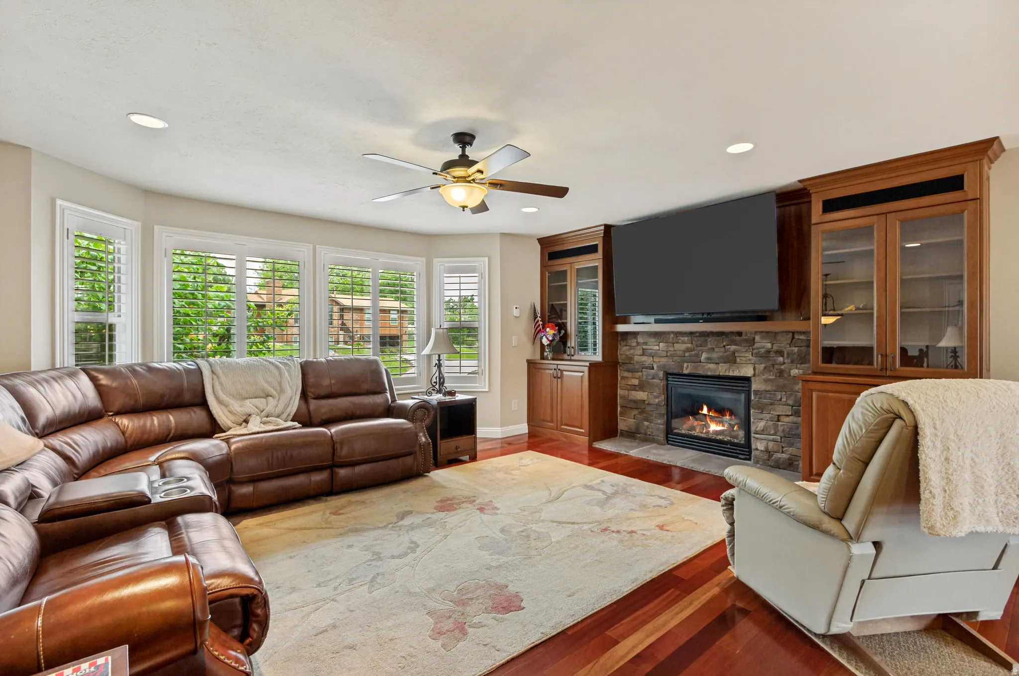Living area featuring rich wood-finish flooring and a bay window with plantation shutters