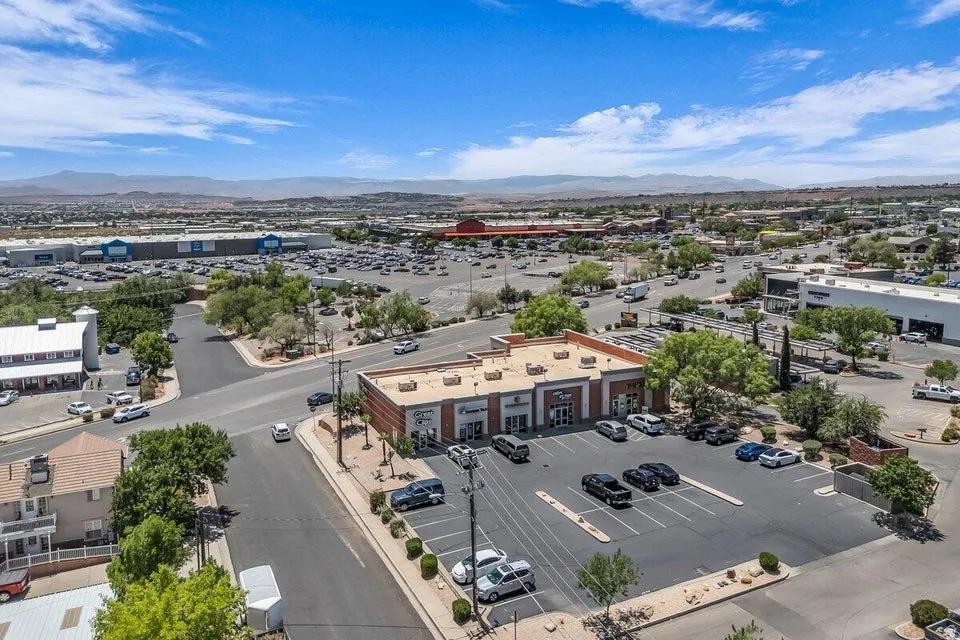 Commercial building featuring a brick facade with stone accents, multiple storefront entrances, and an expansive asphalt parking lot