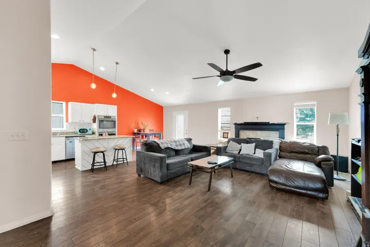 Open-concept living area featuring wood-finish flooring, a vaulted ceiling, and recessed lighting and fireplace.