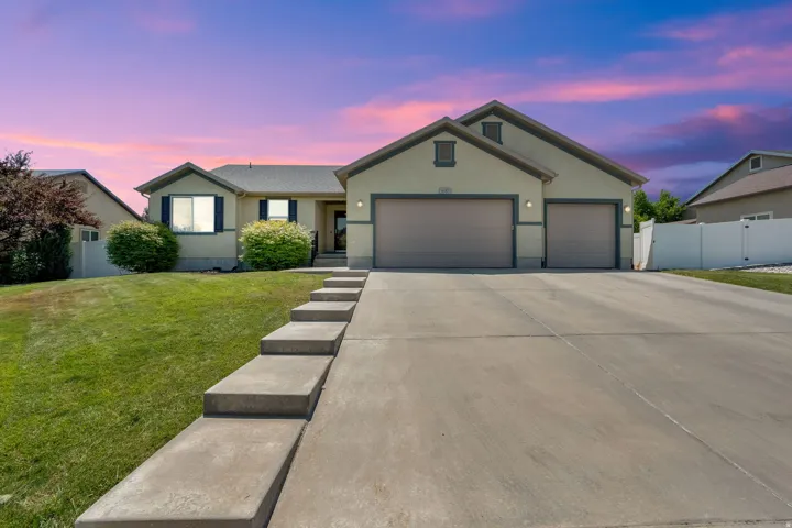 Contemporary stucco exterior with a multi-car garage, concrete driveway, and landscaped front lawn