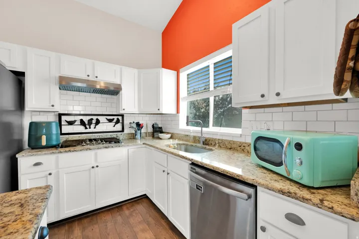 Kitchen featuring white cabinetry, granite countertops, a stainless steel dishwasher, and a subway tile backsplash