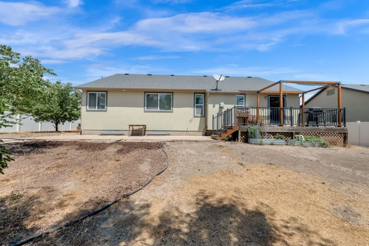 Rear exterior featuring a multi-level deck with black railing, a pergola structure, and a stucco finish