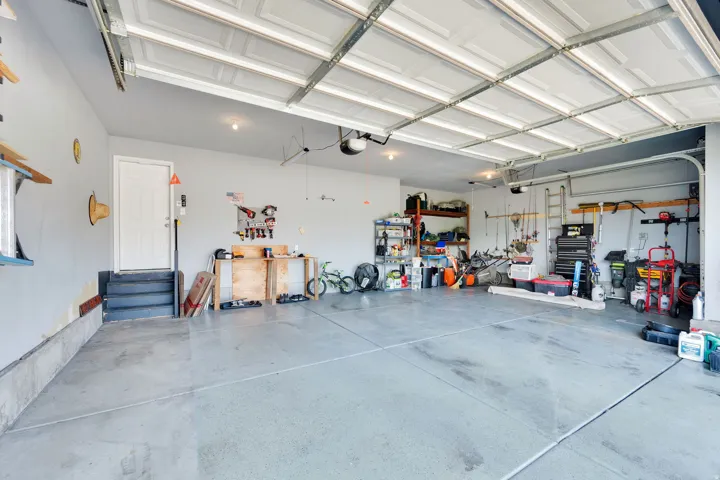 Spacious garage featuring a concrete floor, overhead lighting, and white panel garage doors