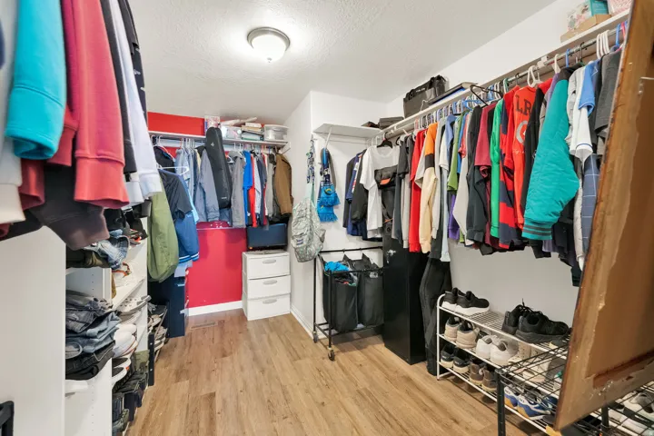 Spacious walk-in closet featuring wood-finish flooring