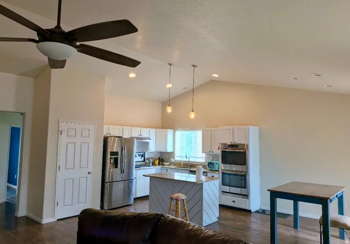 Vaulted ceilings, wood-finish flooring, white cabinetry, stainless steel appliances, and recessed lighting - fresh new updated paint.