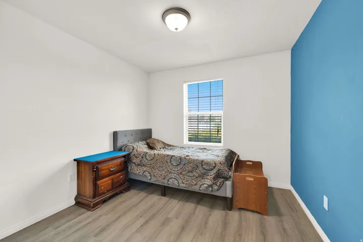 Bedroom featuring light wood-finish flooring, white walls, and a single accent wall in blue
