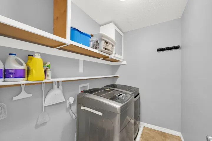 Utility area featuring light gray walls, open shelving, a built-in cabinet, and tile flooring