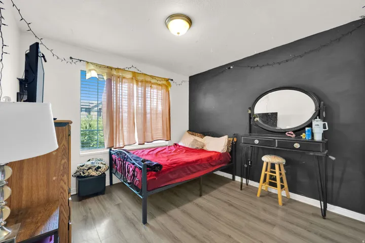 Room with light wood-finish flooring, a white ceiling with a flush-mount light fixture, and white baseboards