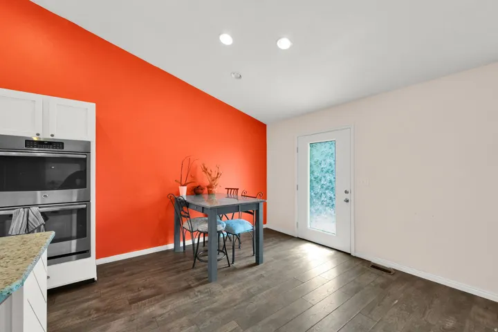 Kitchen dining area featuring a vaulted ceiling and dark wood-finish flooring - walls have been repainted.