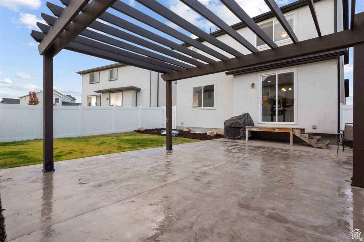 Expansive stamped concrete patio featuring a dark wood-finish pergola
