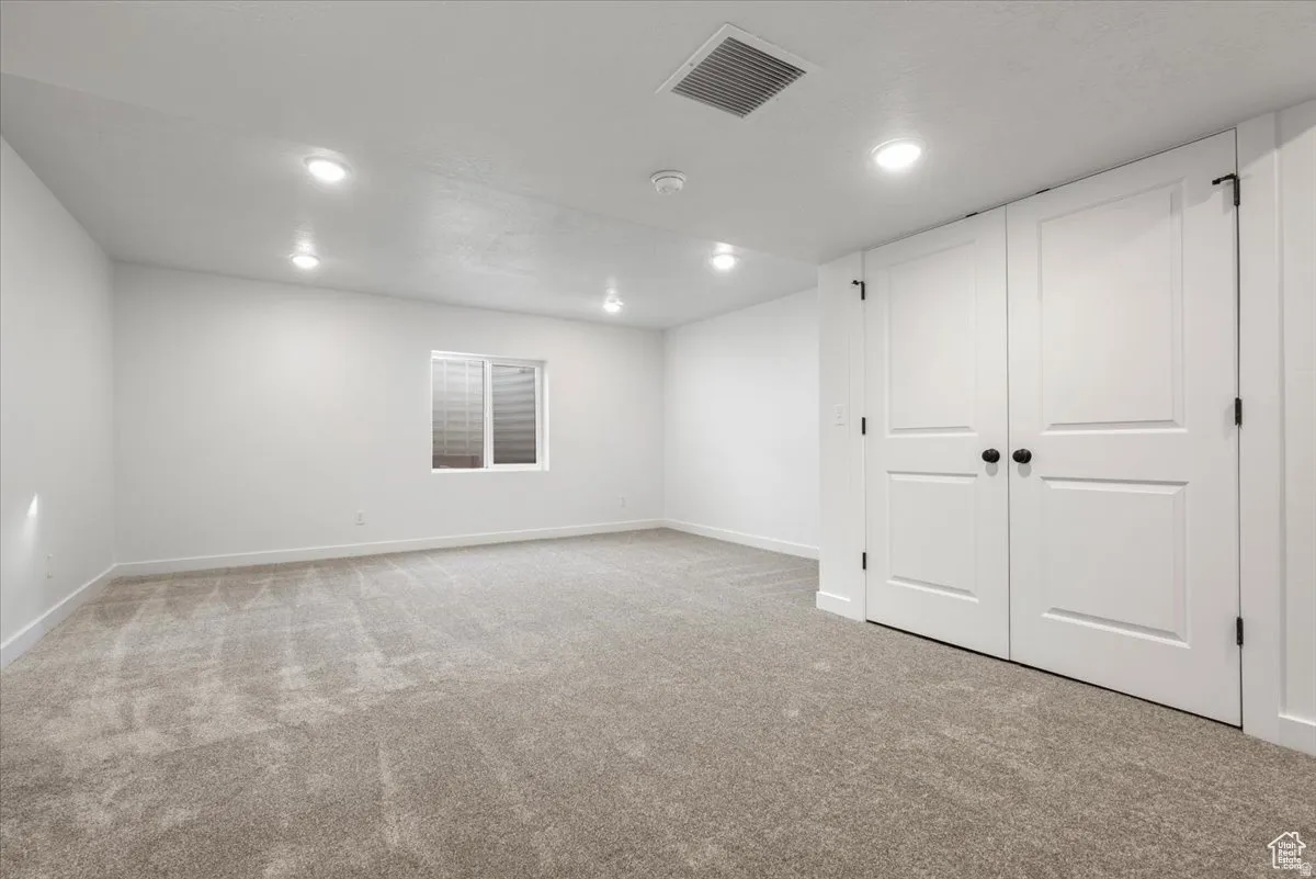 Spacious room featuring neutral carpeting and white walls