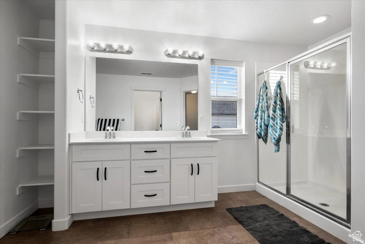 Bathroom featuring a double vanity with white cabinetry, dual sinks, and a large mirror