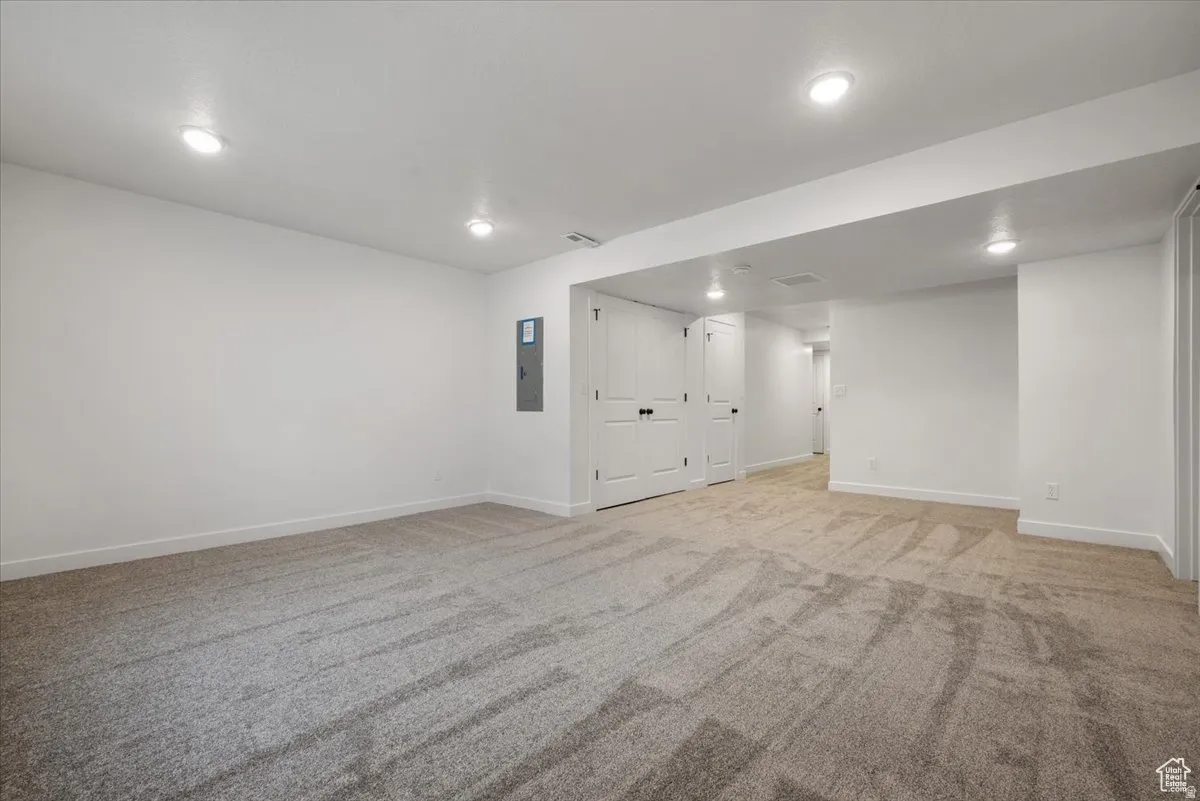Spacious interior room with light-toned carpeting and recessed ceiling lighting