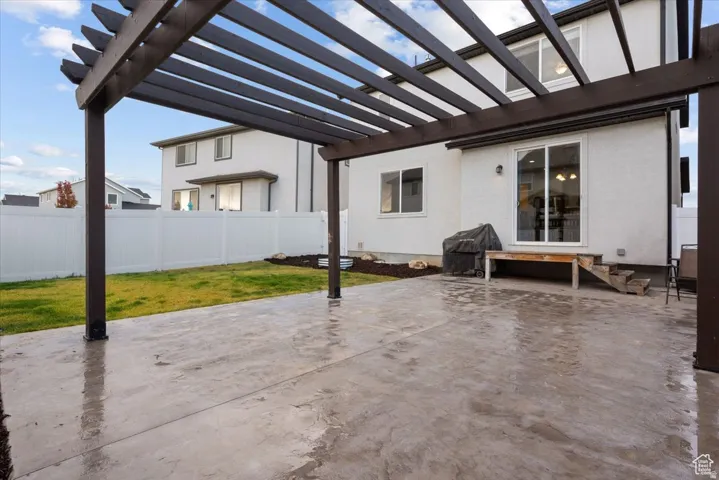 Expansive stamped concrete patio featuring a dark wood-finish pergola
