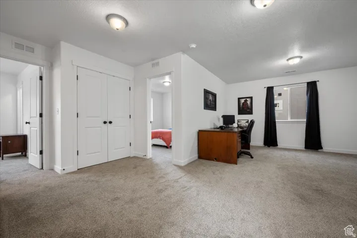 Carpeted room featuring white walls, a double-door closet, and two entryways