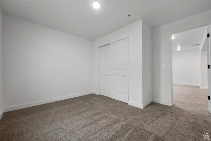 Neutral painted room featuring textured carpeting and a double-door closet with panel detailing